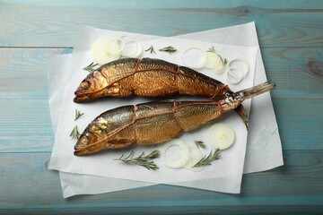 Smoked herrings, rosemary and onion on light blue wooden table, flat lay