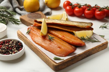 Smoked herrings, spices and tomatoes on white table, closeup