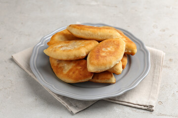 Delicious fried pyrizhky (stuffed pies) on light grey table, closeup