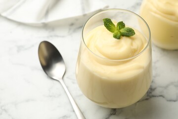 Tasty vanilla pudding with mint served on white marble table, closeup