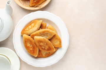 Delicious fried pyrizhky (stuffed pies) on beige table, flat lay. Space for text