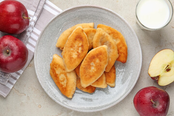 Delicious fried pyrizhky (stuffed pies), apples and milk on light grey table, flat lay