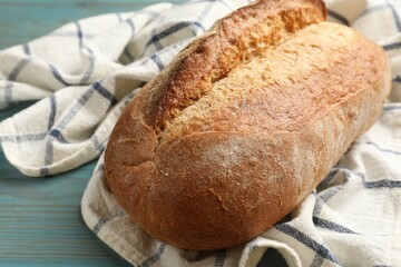 Fresh loaf of bread on light blue wooden table, closeup