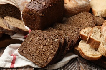 Different types of fresh bread on wooden table, closeup