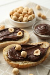 Slices of bread with chocolate spread and hazelnuts on table, closeup