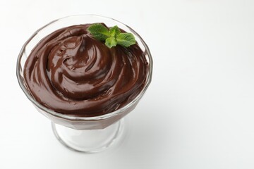 Delicious chocolate pudding with mint in dessert bowl on white table, closeup. Space for text