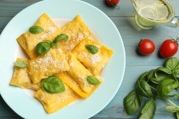 Delicious ravioli with cheese and basil served on light blue wooden table, flat lay