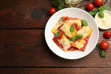 Delicious ravioli with tomato sauce, parmesan cheese and basil on wooden table, flat lay. Space for text