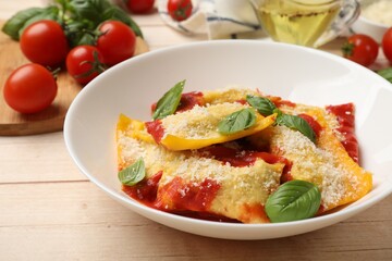 Delicious ravioli with tomato sauce, parmesan cheese and basil on white wooden table, closeup