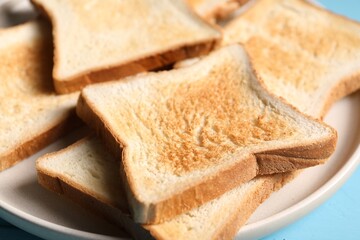 Slices of tasty toasted bread on light blue table, closeup