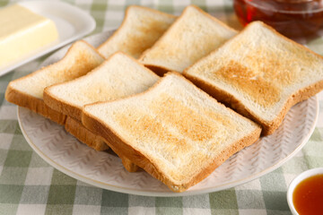 Slices of tasty toasted bread on checkered tablecloth, closeup