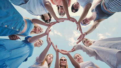 Obraz premium School friends joining hands in a circle under a clear blue sky, displaying teamwork and togetherness