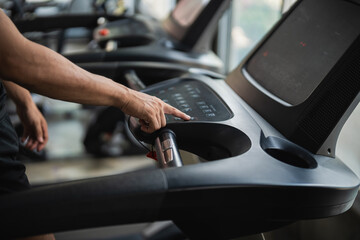Close-up of a sport man using a treadmill, focused on the control panel, fitness equipment in a...