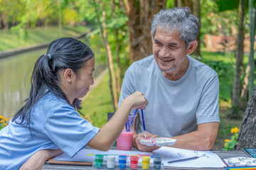 Fototapeta premium grandpa raising curious child and enjoys leisure time painting together in the park