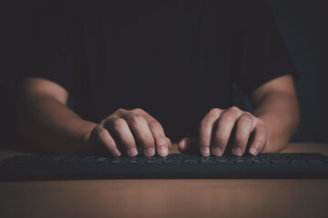 Close-up of hands typing on a keyboard in a dark room, representing cybersecurity, hacking, or late-night programming.