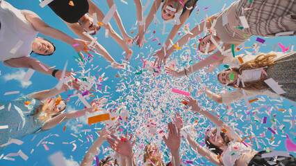 High school graduates joyfully tossing vibrant confetti in the air to celebrate their summer...