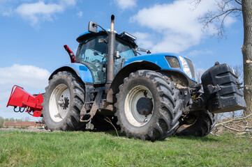 A Blue Tractor equipped with a Field Attachment is positioned under a clear sky