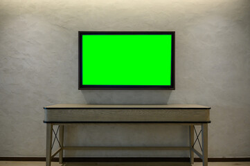 Mockup Television with green screen hanging on white wall. Green blank monitor mockup. TV 4K flat...