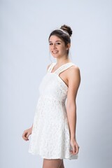 Young woman in white lace dress posing in studio with neutral background