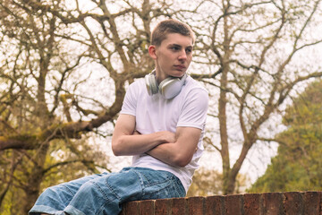 Obraz premium Teenage boy sitting on a brick wall