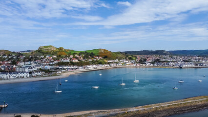 Fototapeta premium Aerial view of small sailing craft on River Conwy with town of Deganwy on opposite shore