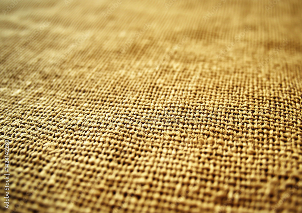 Poster a close up shot of a woven burlap fabric with a shallow depth of field and warm color tones