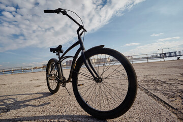 Fototapeta premium Black retro bicycle against the backdrop of a cityscape and sky
