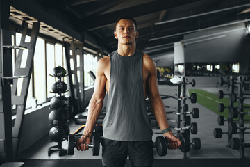 Caucasian man athletic workout weight training biceps muscles with dumbbells in fitness gym. Weight...