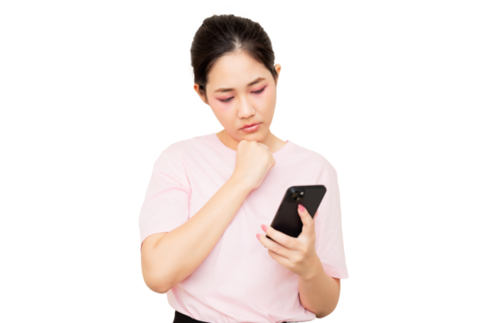 A young woman in a pink shirt is thoughtfully looking at her smartphone.