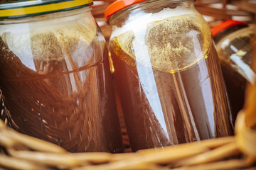 Several sealed glass jars filled with amber honey are arranged in a rustic wicker basket,...