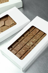 Different tasty Dubai chocolate bars in packages with pistachios and knafeh on grey table, closeup. Space for text