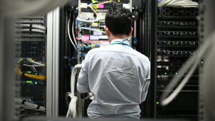 Computer engineer is setting up network in server room,Systems Maintenance Technician,Male engineer working in server room at modern data center	
