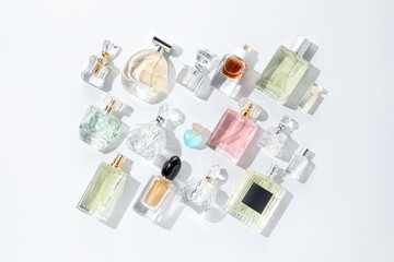Bottles of various perfumes on light background, flat lay