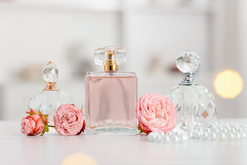 Bottles of perfume and beautiful flowers on white table