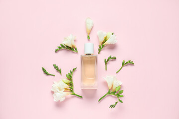 Bottles of perfume and beautiful flowers on pink background, flat lay