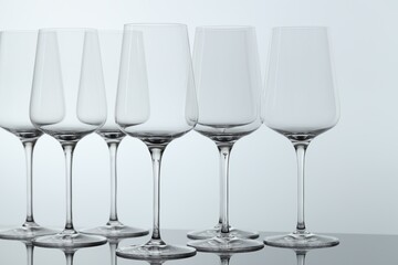 Many clean glass on mirror surface against light background