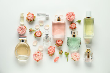 Flat lay composition with bottles of aromatic perfume and beautiful flowers on white background