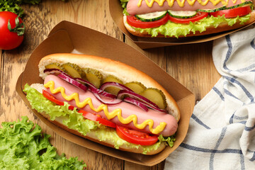 Tasty hot dogs with vegetables on wooden table, flat lay