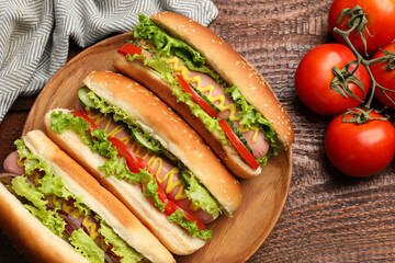 Tasty hot dogs with vegetables on wooden table, flat lay