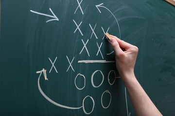 Man drawing American football game scheme on chalkboard, closeup
