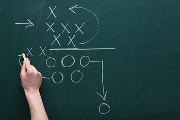 Man drawing American football game scheme on chalkboard, closeup. Space for text