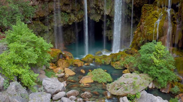 Yerk&ouml;pr&uuml; Waterfall, flowing under a natural rock, is fascinating with its emerald green vegetation. The drone moves towards the heart of the waterfall and rises.