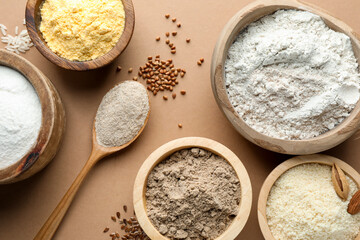 Different types of flour on light brown table, flat lay