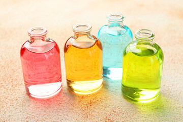 Perfume bottles with aromatic oils on beige textured background, closeup