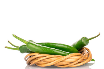 A few pods of ripe organic, spicy green hot pepper with a wicker wreath of twigs, close-up, on a...