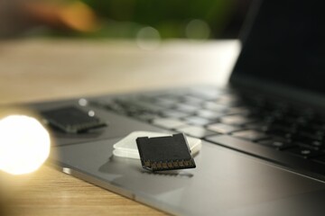 SD memory cards, holder and laptop on wooden table, closeup