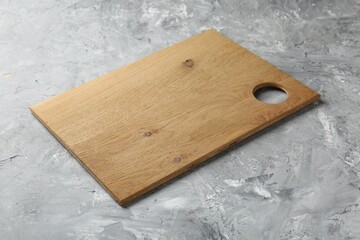 One wooden serving board on light grey textured table, closeup. Space for text