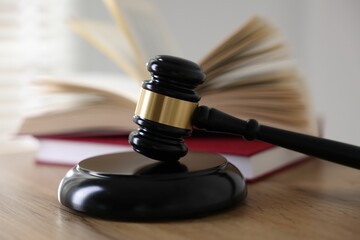 Judge's gavel and books on wooden table indoors, selective focus