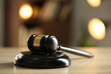 Judge's gavel on wooden table against blurred background, closeup