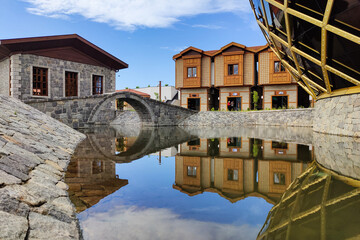 Reflection image of houses built with regional architecture and stone arch blind.